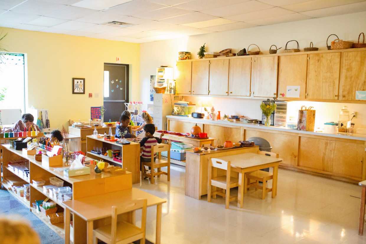 children sitting at tables learning in a guidepost montessori classroom