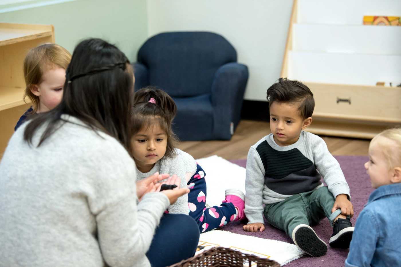 children sitting on the floor with a guide in a guidepost montessori classroom