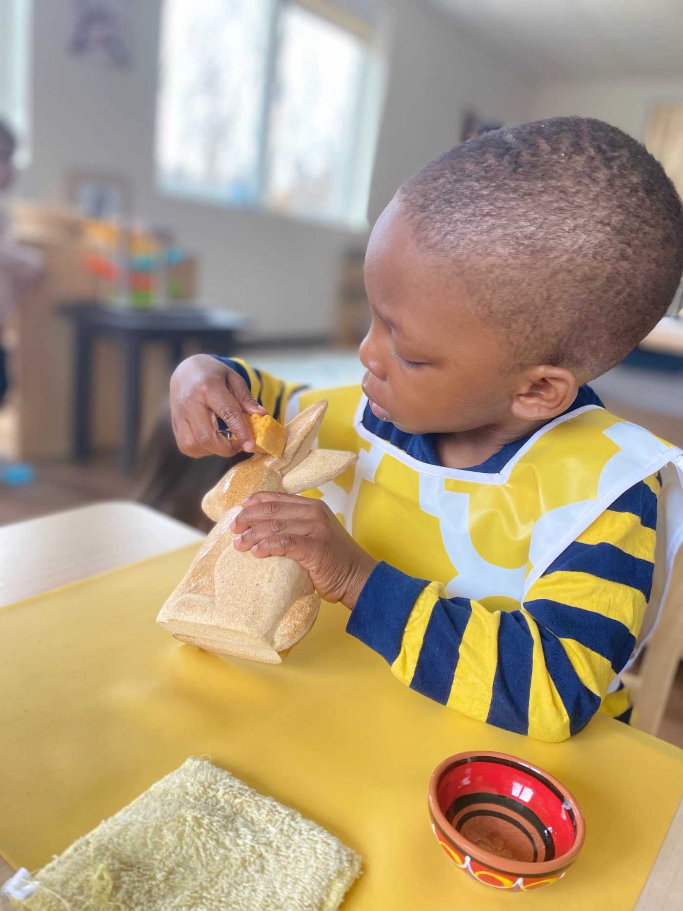 child holding a wooden rabbit in a guidepost montessori classroom