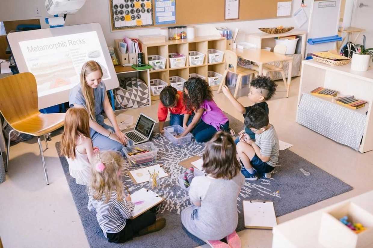 children sitting on the floor at guidepost montessori learning with their guide